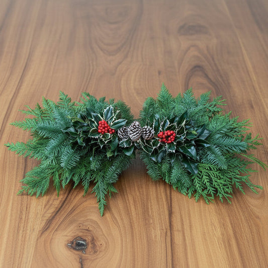 Decorative greenery with berries and pinecones on a wooden surface