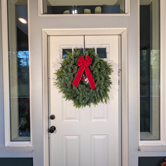 Christmas wreath with a red bow on a white door
